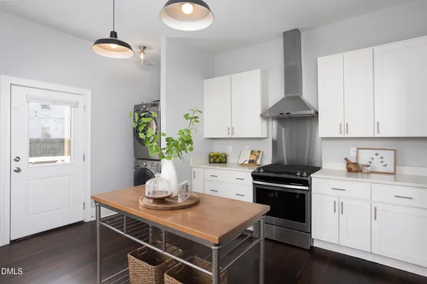 a kitchen with stainless steel appliances a stove a chimney a sink and cabinets