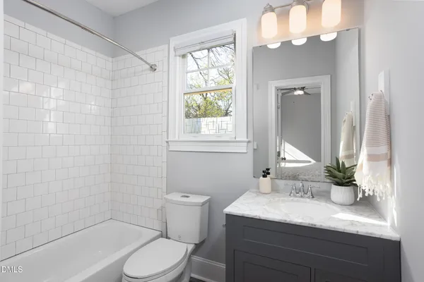 a bathroom with a granite countertop sink a toilet a mirror and shower