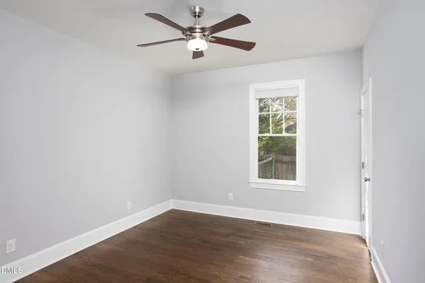an empty room with wooden floor closet and windows