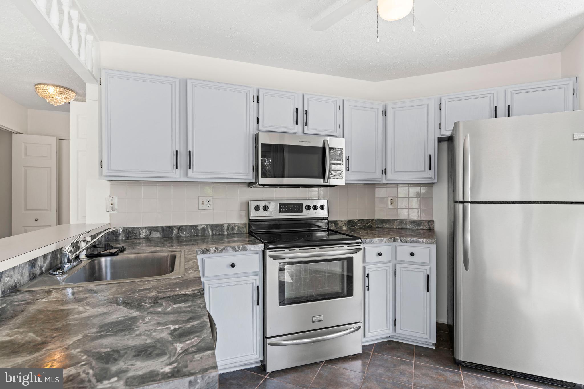 31 Beagle Run, Unit 88 Nottingham, MD 21236 - Photo 5 of 43 a kitchen with a refrigerator stove and white cabinets