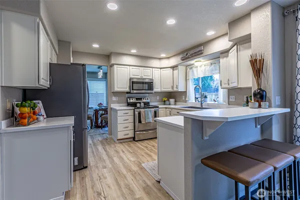 a kitchen with stainless steel appliances a microwave sink stove refrigerator and cabinets