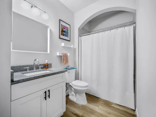 a bathroom with a granite countertop sink toilet and a mirror