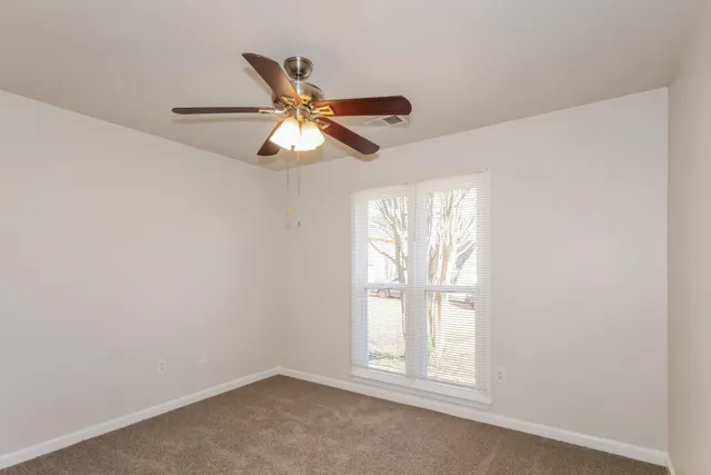 an empty room with windows and fan