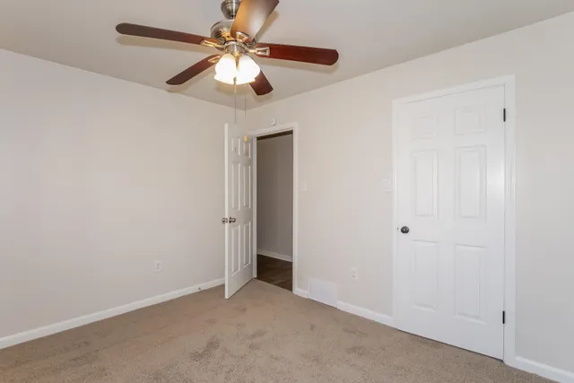 an empty room with a chandelier fan and a ceiling fan