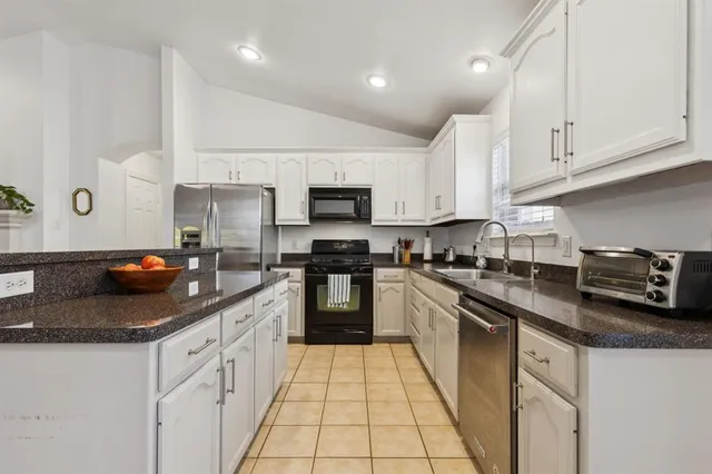 a kitchen with stainless steel appliances granite countertop a sink a stove and cabinets