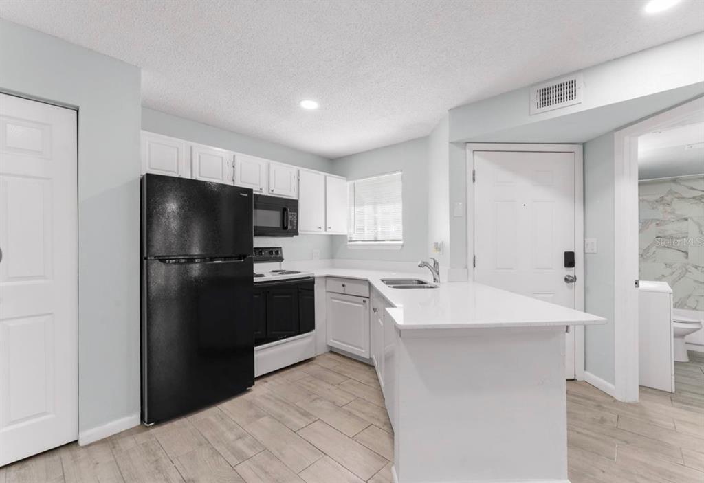 1908 Lake Atriums Circle, Unit 3 Orlando, FL 32839 - Photo 2 of 17 a kitchen with a sink a stove a refrigerator and a microwave
