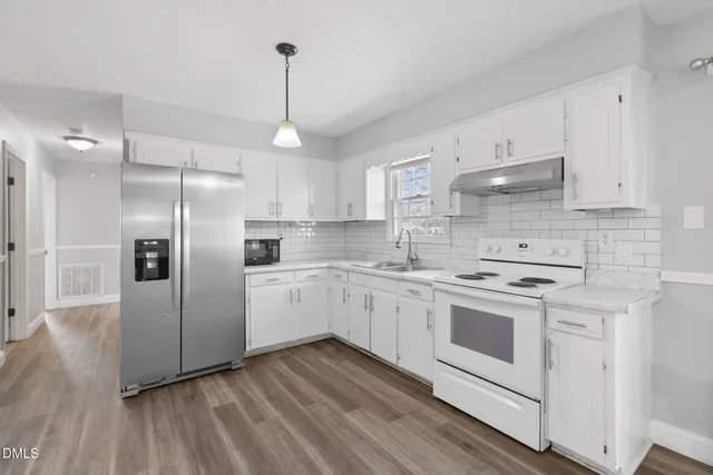 a kitchen with stainless steel appliances granite countertop a refrigerator a sink dishwasher a stove and white countertops with wooden floor