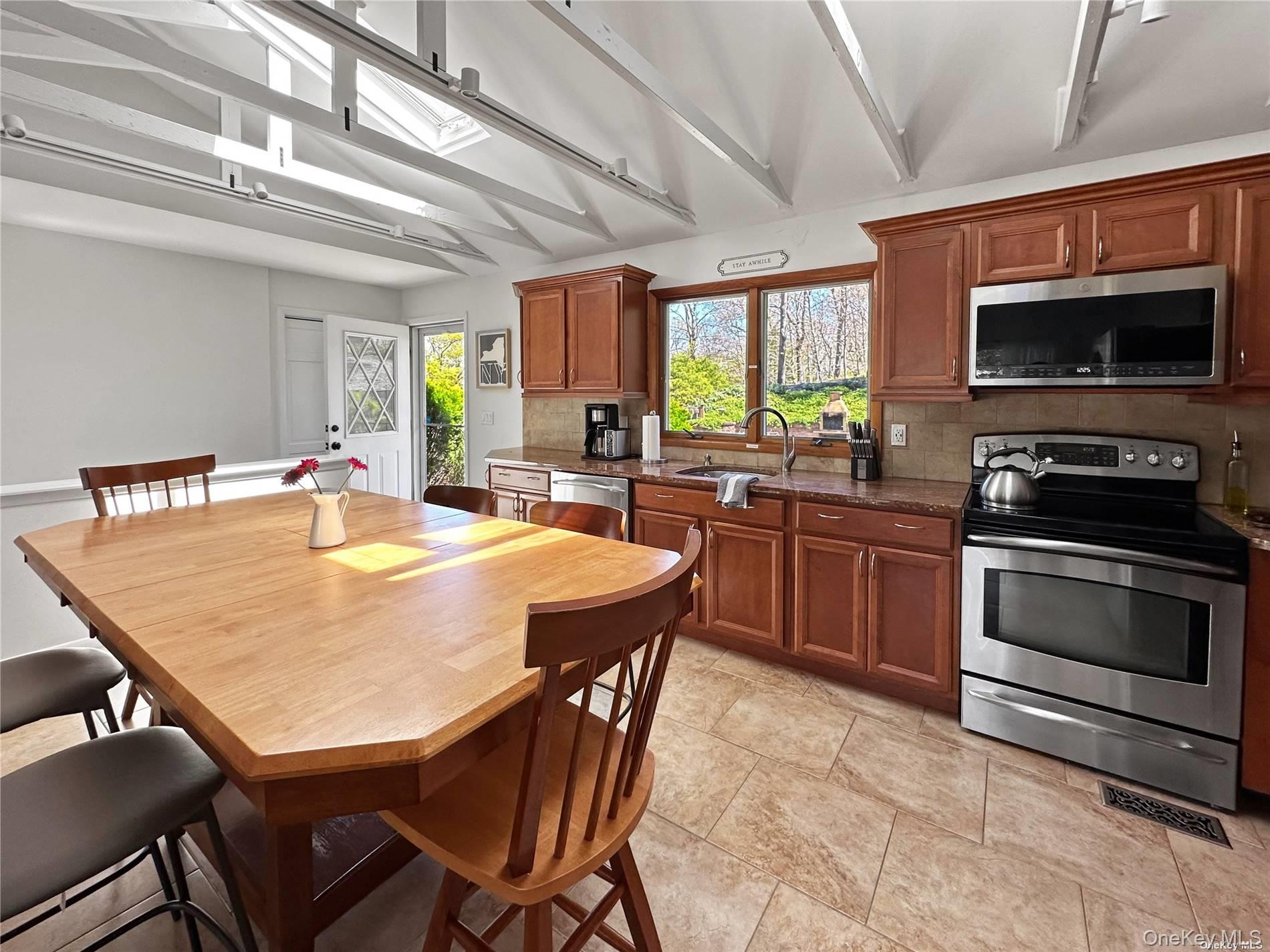 126 Overhill Road Wading River, NY 11792 - Photo 4 of 23 a kitchen with a stove a sink dishwasher a dining table and chairs with wooden floor