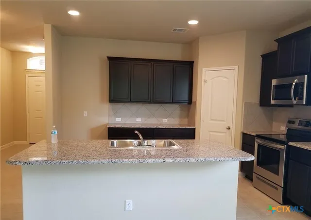 a kitchen with stainless steel appliances granite countertop a sink stove and microwave