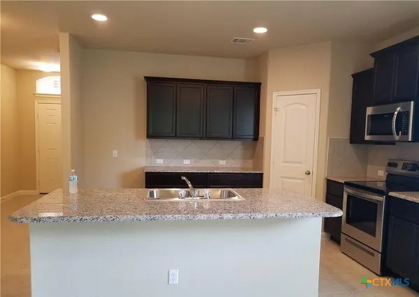 a kitchen with stainless steel appliances granite countertop a sink stove and microwave