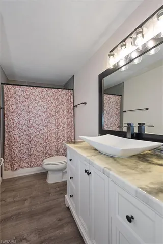 a bathroom with a granite countertop toilet sink and mirror