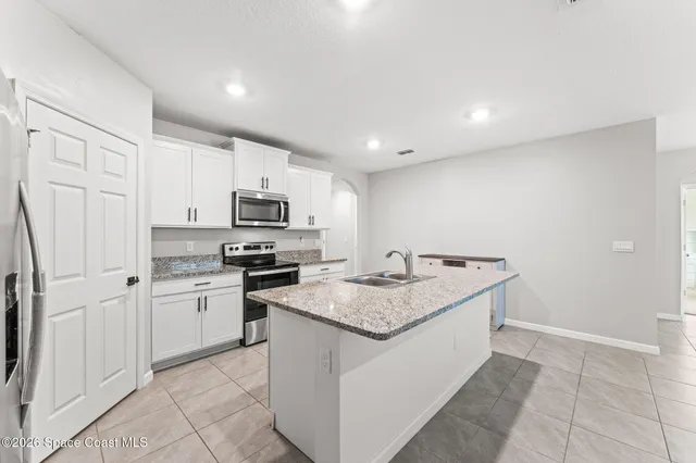 a kitchen with granite countertop a sink stove and refrigerator