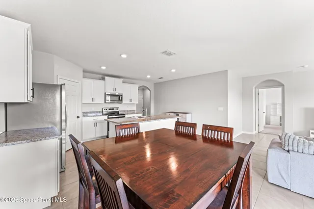 a living room with stainless steel appliances furniture a dining table and chairs