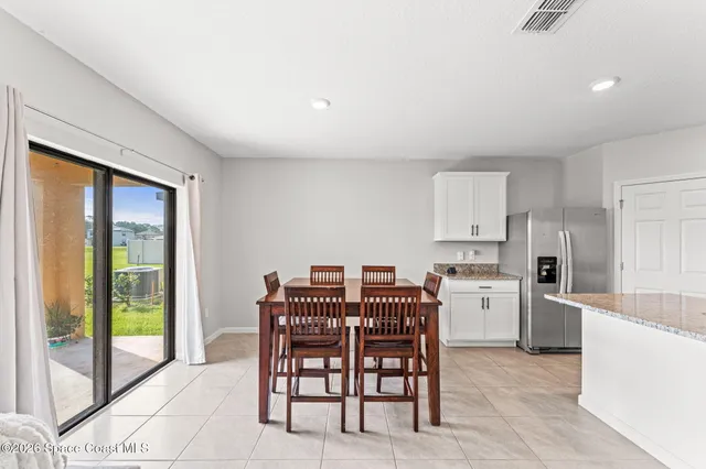 a kitchen with stainless steel appliances a table and chairs in it