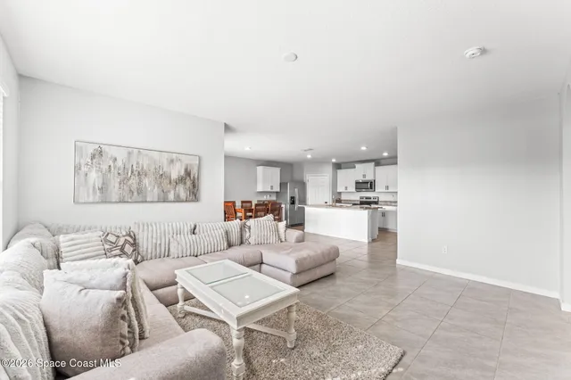 a living room with furniture and a view of kitchen