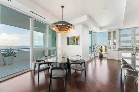 a living room with furniture couches and a dining table with wooden floor
