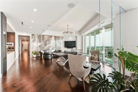 a living room with stainless steel appliances kitchen island a large window and a potted plant