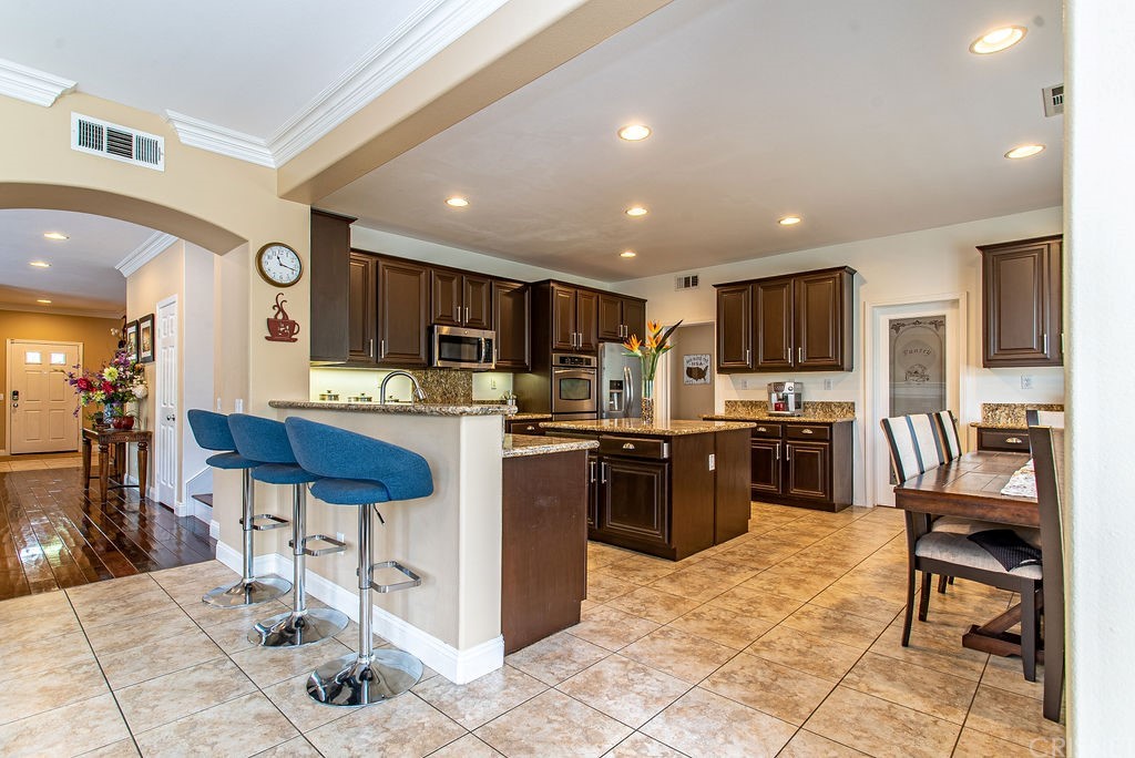 25054 Oliver Way Stevenson Ranch, CA 91381 - Photo 11 of 53 a kitchen with stainless steel appliances kitchen island granite countertop a refrigerator and cabinets