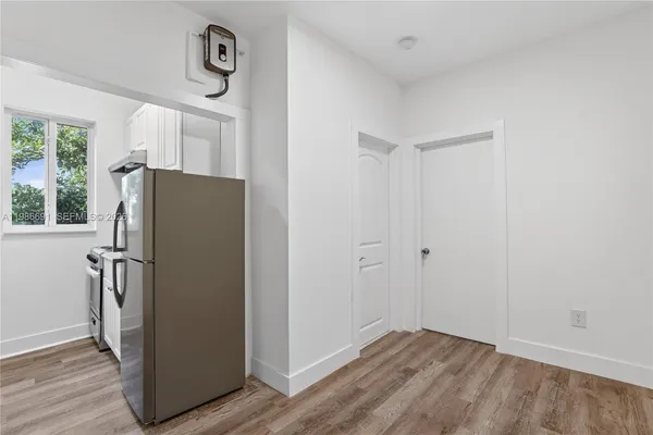 a view of a refrigerator in kitchen and an empty room