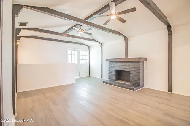 a view of a livingroom with a fireplace a ceiling fan and wooden floor