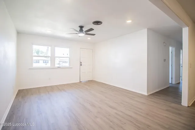 a view of an empty room with a window and wooden floor