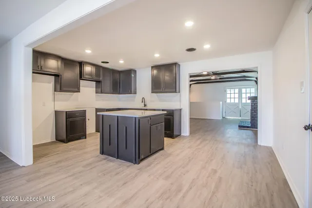 a kitchen with stainless steel appliances granite countertop a refrigerator oven a sink dishwasher and white cabinets with wooden floor