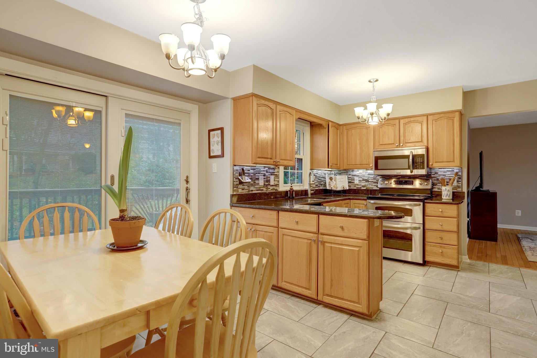 8705 Side Saddle Road Springfield, VA 22152 - Photo 21 of 73 a kitchen with stainless steel appliances granite countertop a sink a stove a dining table and chairs