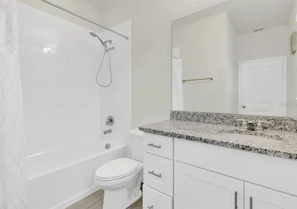 a bathroom with a granite countertop sink a toilet and shower