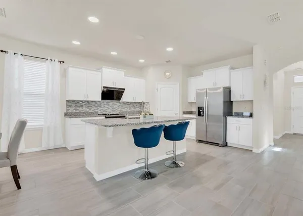 a kitchen with a refrigerator a stove top oven and white cabinets