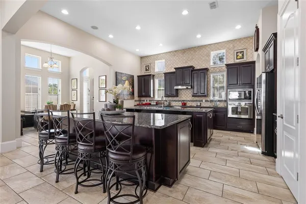 a large kitchen with granite countertop a large counter top a sink stainless steel appliances and cabinets