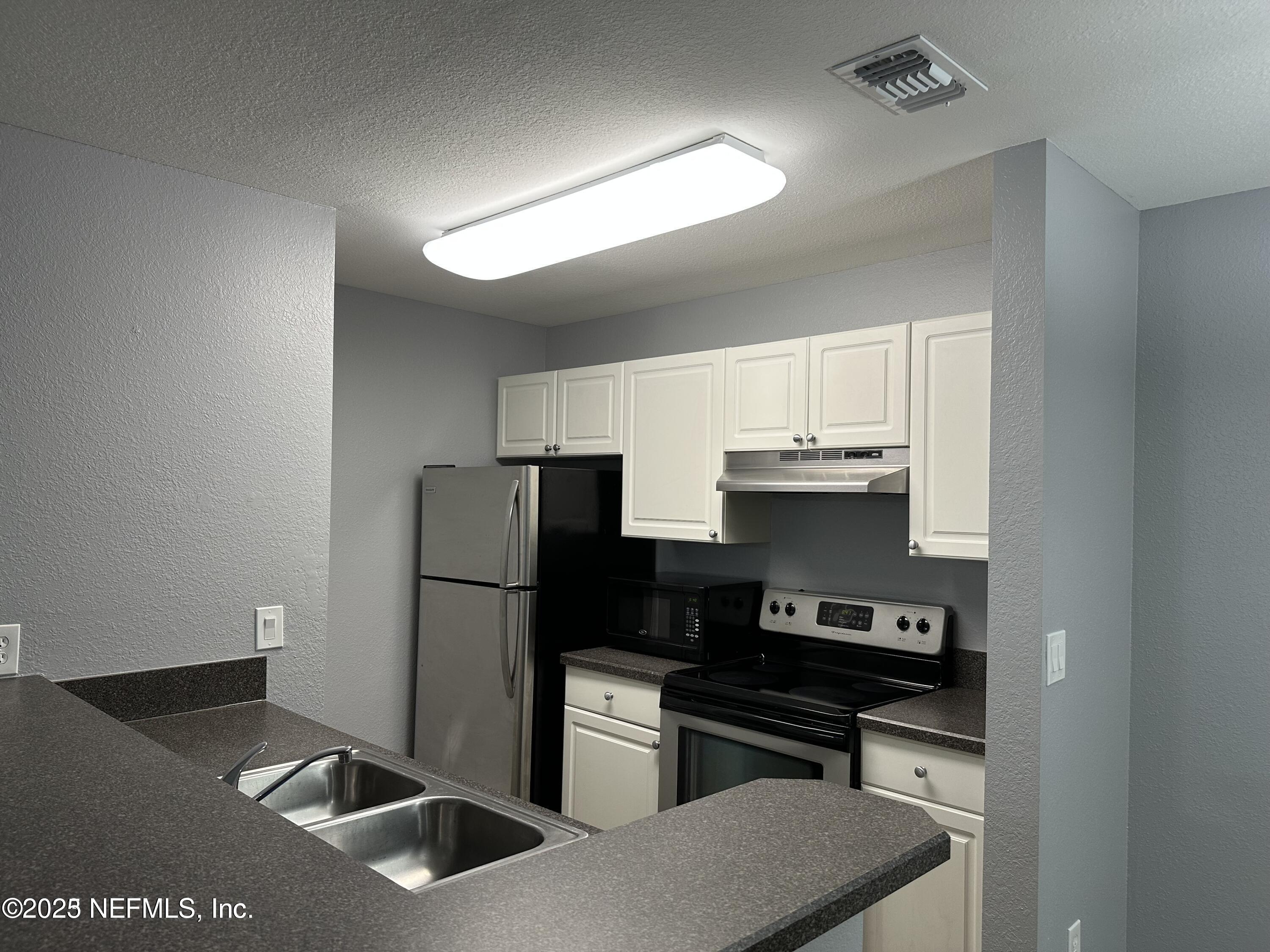 1717 County Road 220, Unit 2102 Fleming Island, FL 32003 - Photo 5 of 10 a kitchen with stainless steel appliances a refrigerator a stove and a sink
