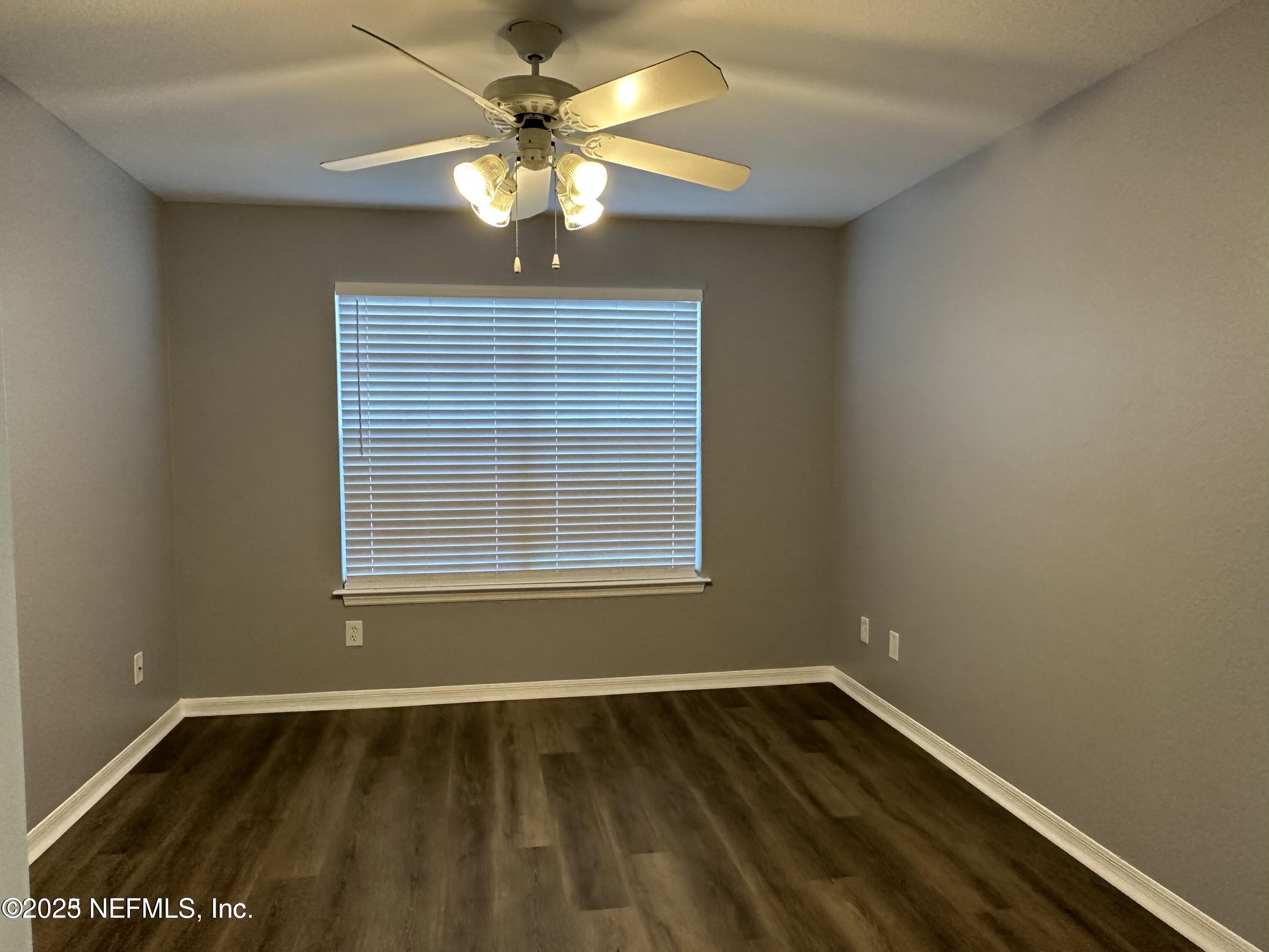 1717 County Road 220, Unit 2102 Fleming Island, FL 32003 - Photo 9 of 10 a view of an empty room with wooden floor and a window