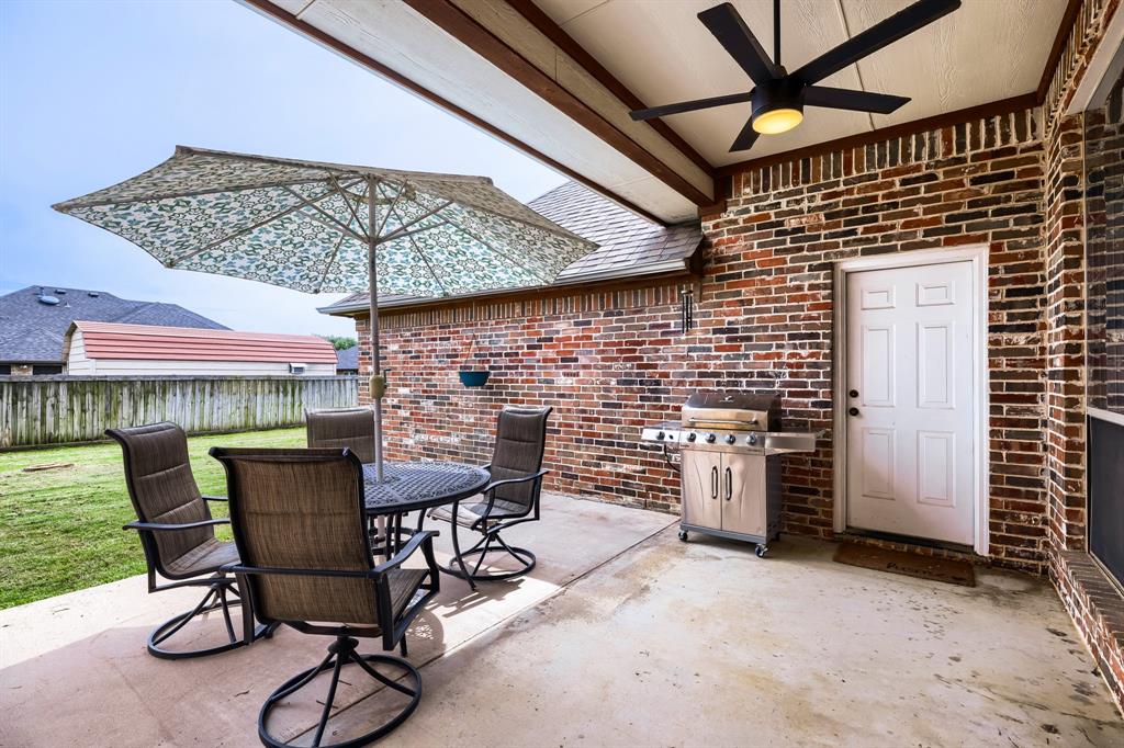 603 Ash Street Pilot Point, TX 76258 - Photo 25 of 28 Covered patio featuring brick siding, a concrete floor, an overhead ceiling fan, and a fenced backyard