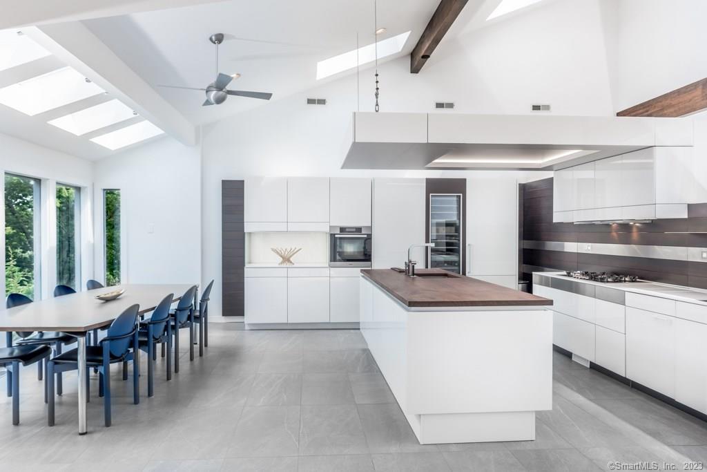 a kitchen with stainless steel appliances kitchen island granite countertop a table chairs sink and cabinets