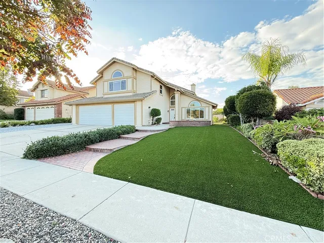 a view of a white house next to a yard with big trees