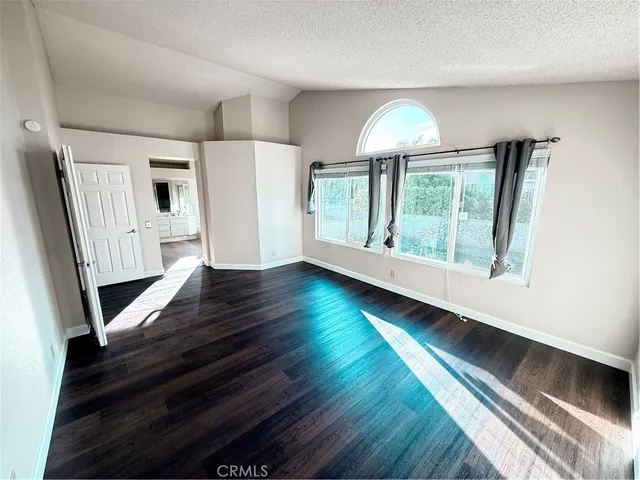 an empty room with wooden floor chandelier fan and windows