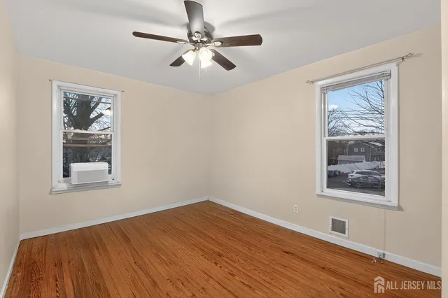 a view of empty room with wooden floor and fan