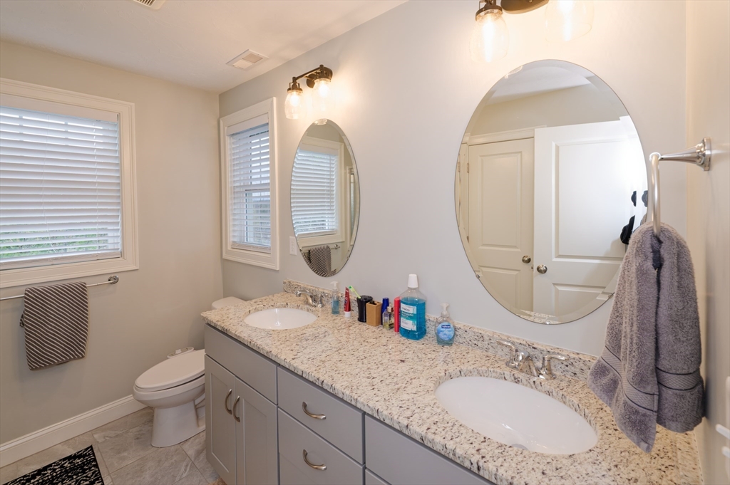 1202 Hazelwood Way, Unit 1202 Clinton, MA 01510 - Photo 21 of 38 a bathroom with a granite countertop toilet a sink and a mirror
