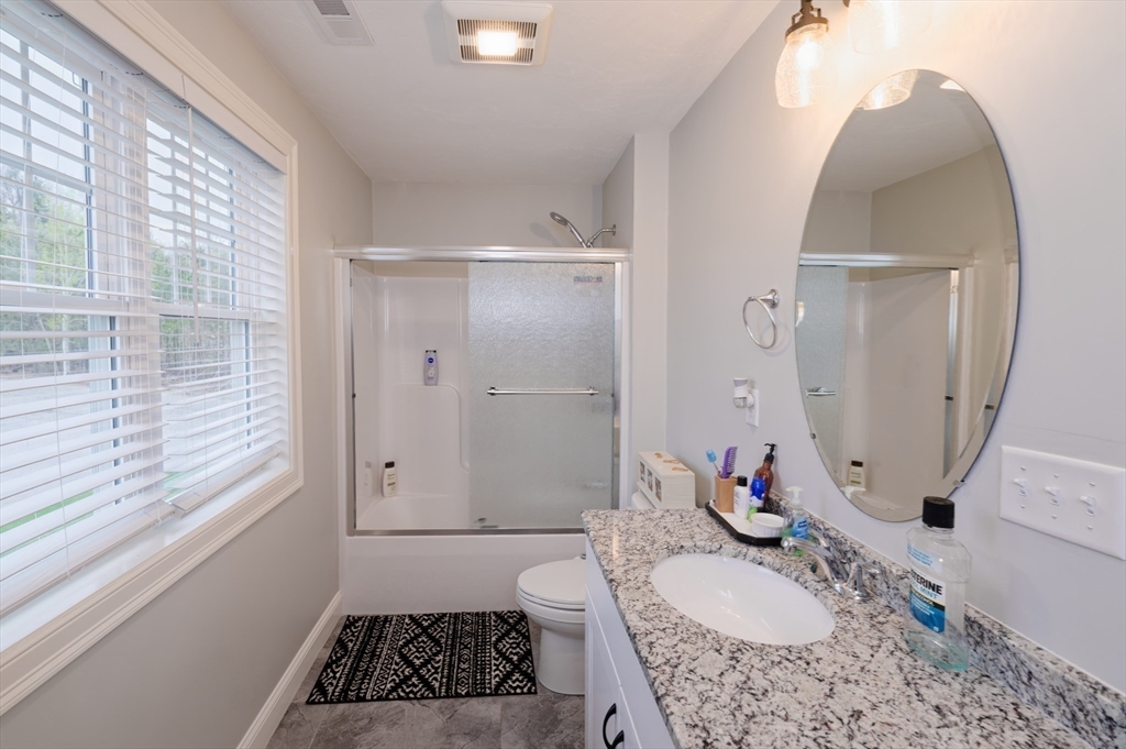 1202 Hazelwood Way, Unit 1202 Clinton, MA 01510 - Photo 26 of 38 a bathroom with a granite countertop sink a toilet a tub and shower
