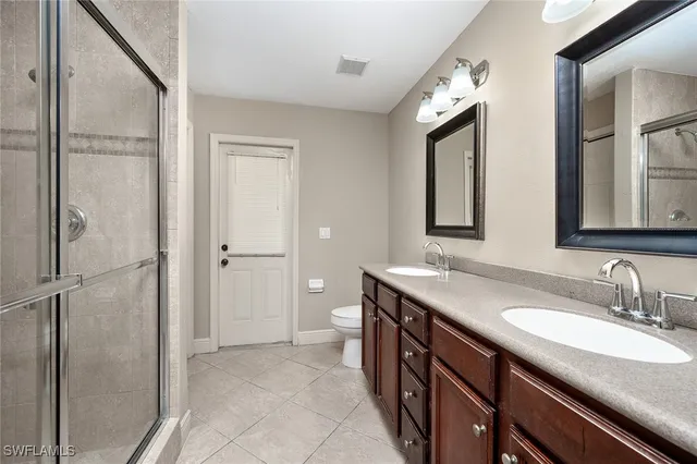a spacious bathroom with a granite countertop sink two mirror and a shower