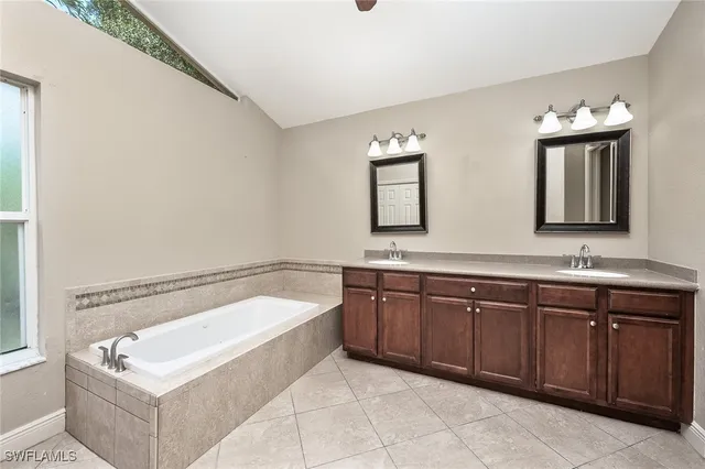 a spacious bathroom with a tub sink and mirror