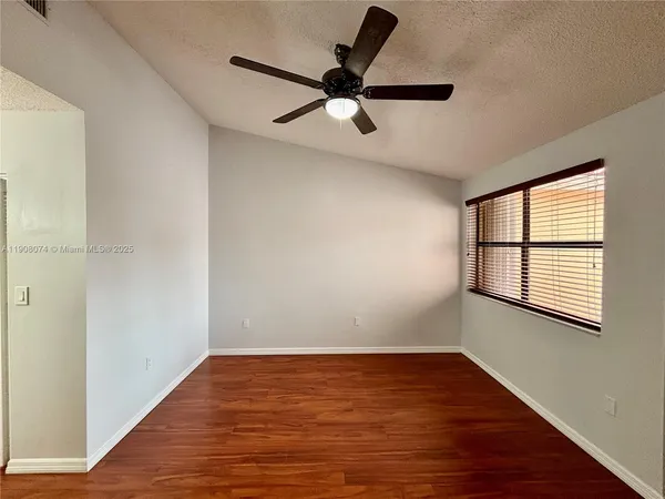 a view of empty room with wooden floor and fan