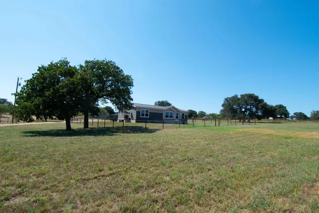 a yellow house with a big yard and large trees