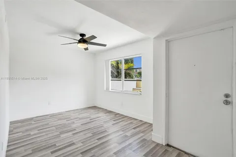 a view of a room with wooden floor and a ceiling fan