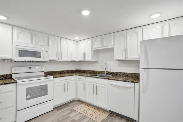 a kitchen with granite countertop white cabinets and white appliances