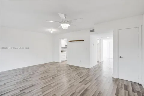 an empty room with wooden floor and ceiling fan
