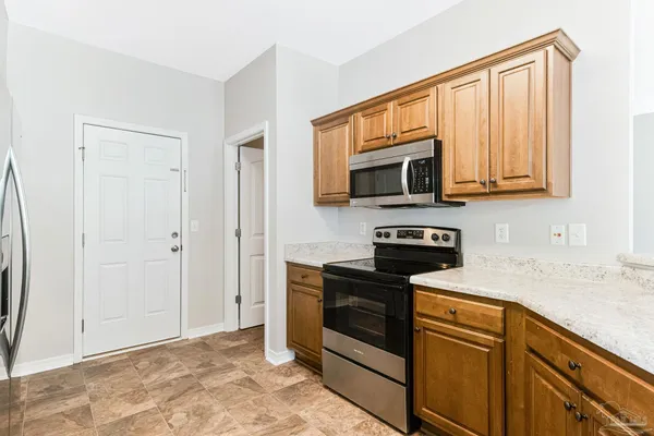 a kitchen with granite countertop a stove top oven microwave and refrigerator