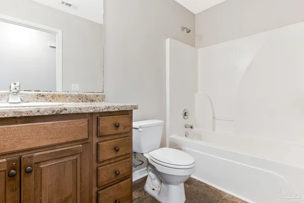 a bathroom with a granite countertop toilet sink and mirror