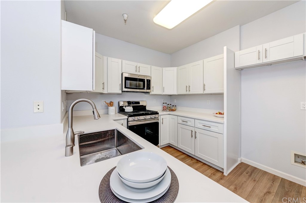 100 South Alameda Street, Unit 210 Los Angeles, CA 90012 - Photo 3 of 52 a kitchen with stainless steel appliances a sink a stove a microwave and cabinets