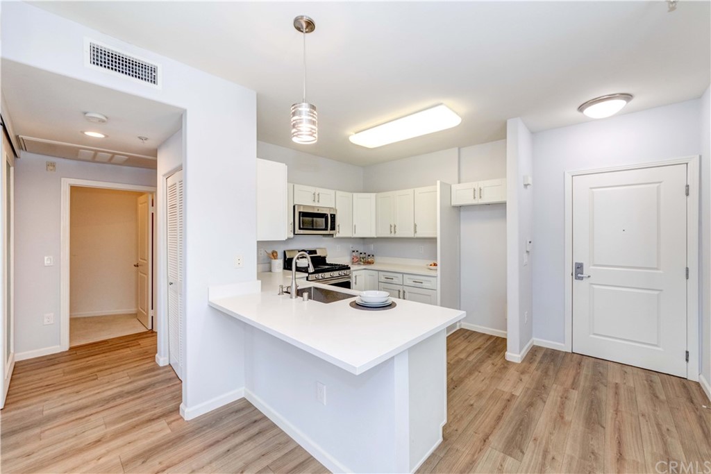 100 South Alameda Street, Unit 210 Los Angeles, CA 90012 - Photo 4 of 52 a kitchen with white cabinets and stainless steel appliances